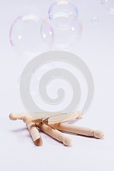 Wooden dolly pegs and bubbles on white background