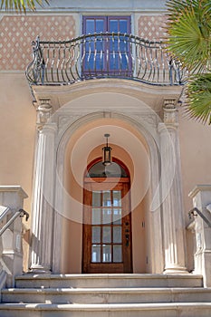 Wooden door with arched transom window below the balcony with double door at San Francisco, CA