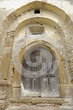 Wooden door in carved, stone wall, Copsa Mare, Romania