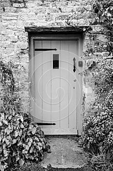 Wooden door entrance into rural cottage house in Bibury, Cotswolds, Egland, UK