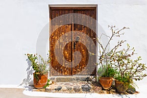 Wooden door with flowers. White cycladic architecture in Santorini island, Greece