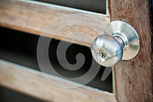 wooden door with grill, stainless door knob or handle on wooden door in beautiful lighting.