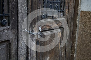 Wooden door of an old house that is closed with a padlock and chain