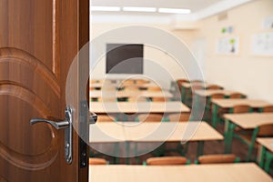 Wooden door open into empty classroom