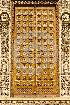Wooden door and ornament on wall of palace in Jaisalmer fort, India. photo