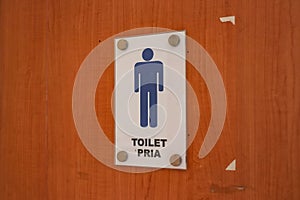 A wooden door with a men\'s toilet sign attached to it photo