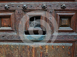 Wooden door with a rusty metal mailbox and a peephole.