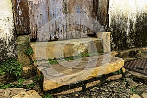 Wooden door and stairs and stone sidewalk in an old house of colonial architecture