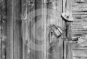 Wooden door surface with handle, old padlock, old metal and wooden latches. Wooden background and space for text.