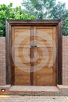 Wooden door and wood frame with the Bronze Knocked Chinese Lion head style on it. This is middle of the brick wall in the garden