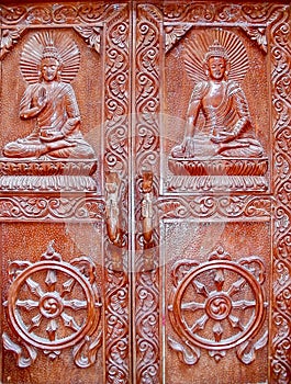 Wooden doors of the old Buddhist monastery with images of Buddha and the dharma wheel in Kathmandu, Nepal