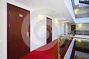 Wooden doors, red carpet on floor and handrails of balconies