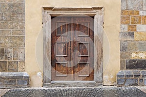 A wooden double door with rectangle door frame in a stone wall