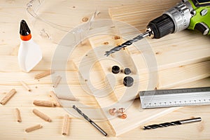 Wooden dowel joint pins drill glue wood planks safety glasses cordless screwdriver and tools spruce background. Carpenter industry