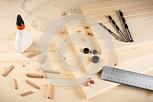 Wooden dowel joint pins drill glue wood planks safety glasses and tools spruce background. Carpenter industry funiture making