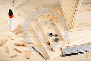 Wooden dowel joint pins drill glue wood planks safety glasses and tools spruce background. Carpenter industry funiture making