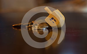 Wooden Dreidel Resting on Pile of Coins