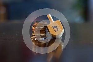 Wooden Dreidel Resting on Stack of Coins