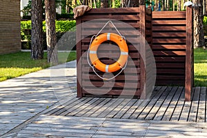 Wooden dressing changing room with orange lifebuoy at recreation area near pond, pool or lake at forest eco-frinedly resort. Cabin