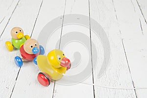 Duck pull toy with a string on a white wooden background