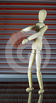 Wooden dummy with basketball in front of a jalousie plays with the ball