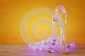 Wooden dummy holding shiny light bulb. New idea concept