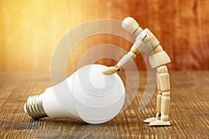 Wooden dummy with LED light bulb on wooden background