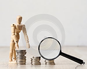 Wooden dummy and stacks of white coins, the concept of accumulation of cash, donation, subsidy