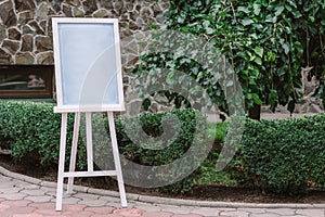 Wooden easel with blank canvas outdoos. Space for text