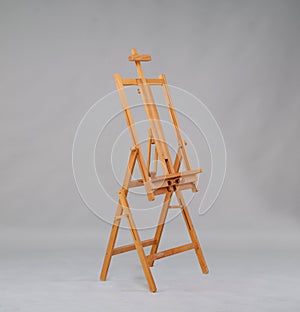 Wooden easel in the studio on a gray background