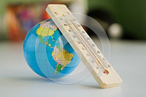 Wooden eco-friendly thermometer and globe in the interior of room or classroom. Climate change and global warming. Temperature in