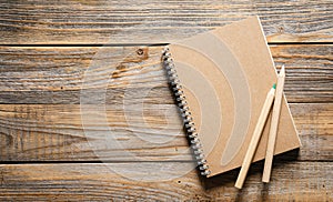 Wooden eco pencils and recycled notebook on a wooden background, top view.