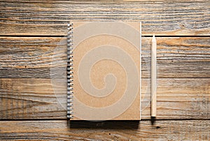 Wooden eco pencils and recycled notebook on a wooden background, top view.