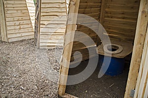 Wooden ecological composting toilet on countryside with sawdust