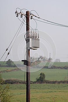 Wooden electricity pole with wires, insulators and transformer