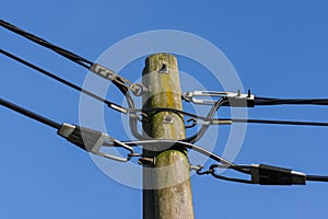 Wooden electricity post against blue sky