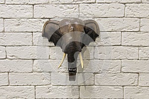 Wooden elephant head hanging on a white brick wall
