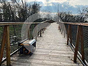 Wooden elevated pathway in a forest with a generator placed on the walkway photo