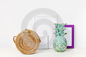 Wooden empty frames for a photo, wooden emerald pineapple, fashionable handmade natural organic rattan bag on a background of a wh