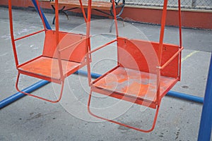 Wooden and Empty red and blue chain swings in children playground . chain swings hanging in garden . Childs swing in a park