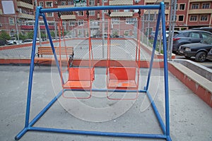 Wooden and Empty red and blue chain swings in children playground . chain swings hanging in garden . Childs swing in a park