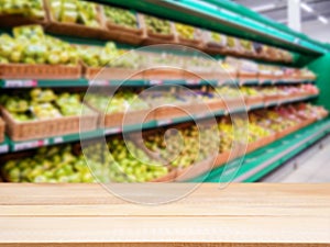 Wooden empty table in front of blurred supermarket fruits shelf