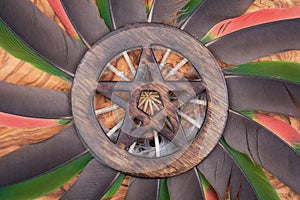 Wooden encircled Pentagram symbol in the middle of a circle made of colorful parrot feathers. Five elements