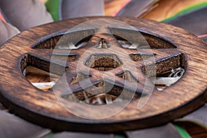 Wooden encircled Pentagram symbol in the middle of a circle made of colorful parrot feathers. Five elements