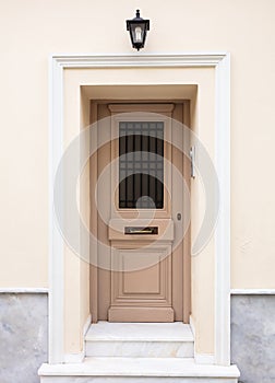 Wooden entrance door, beige color wall background, residential building in old town of Plaka, Athens Greece