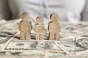 Wooden Family Figures on Money Stack for Wealth Management and Financial Planning Concept