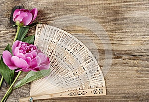 Wooden fan and pink peony on wooden background