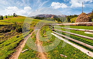 Wooden fence along the dirt road on grassy hills