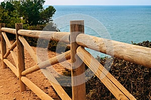 Wooden fence on the coast of Benagil beach in Portugal. View of the Atlantic Ocean on a clear day