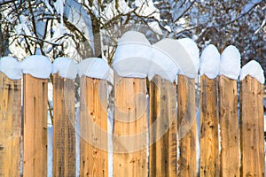 Wooden fence covered with white thick snow